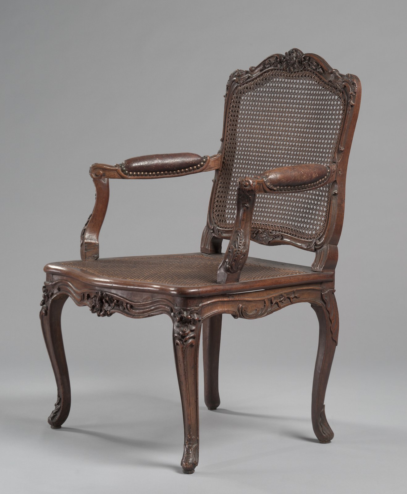 Louis XV caned walnut armchair with leather arm pads and cabriole legs, by Rene Cresson, French, c. 1740