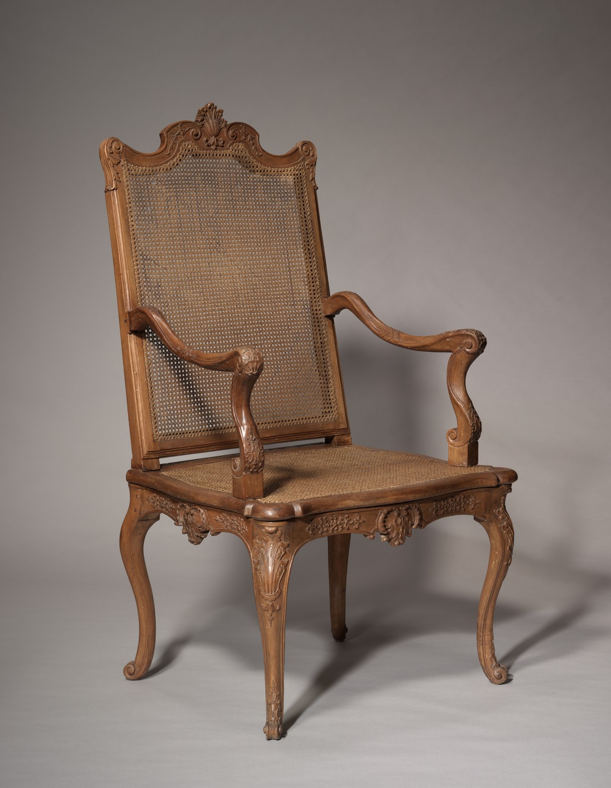 Regence caned walnut fauteuil with carved shell crest, scrolled arms and cabriole legs, French, c. 1715 to 1730