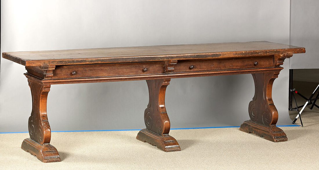 Long carved walnut refectory table on scrolled trestle supports, Italian